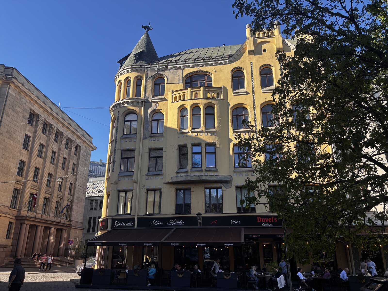The Cat House (Kaķu nams) on Meistaru iela in Riga Old Town, with its yellow Art Nouveau facade and the bronze cat on the corner turret, Latvia.