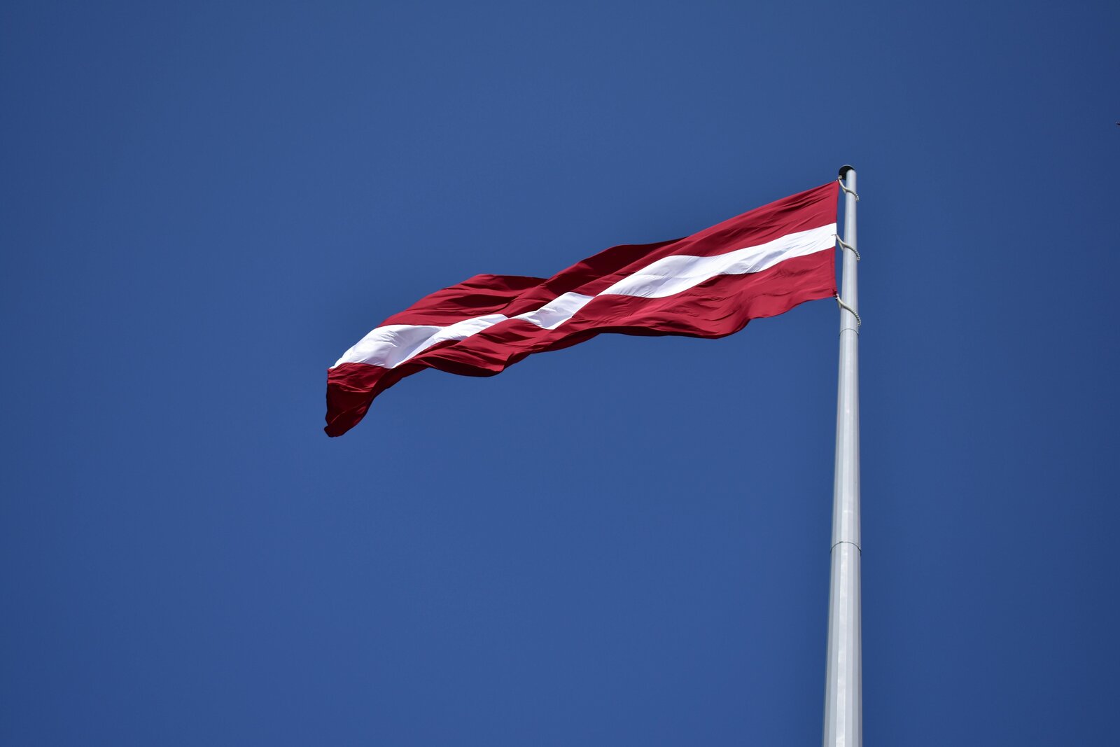 The Latvian flag against a blue sky, the carmine-red and white that Porziņģis wore on his shoulders at the 2024 NBA Finals