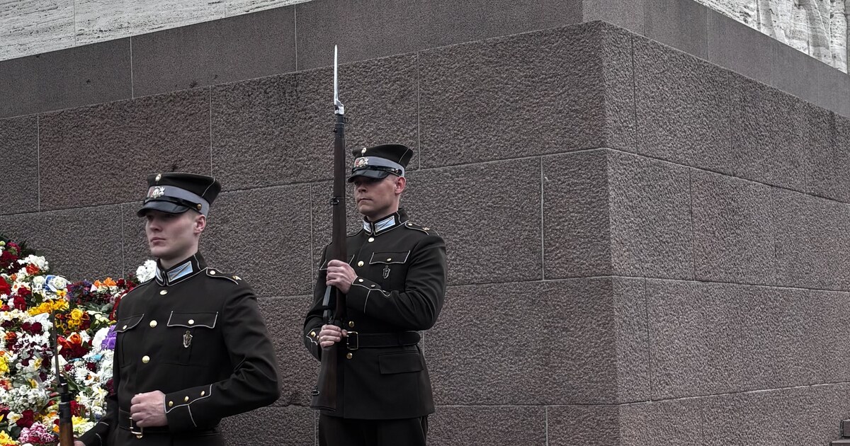 Latvian Army honor guard at the Freedom Monument with a wall of flowers laid against the base, Riga, on Restoration of Independence Day