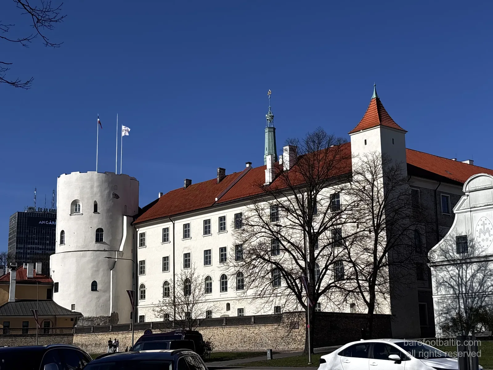 Zamek Ryski (Rīgas pils) z białymi murami, czerwonym dachem i okrągłą wieżą Świętego Ducha w Rydze, na Łotwie.