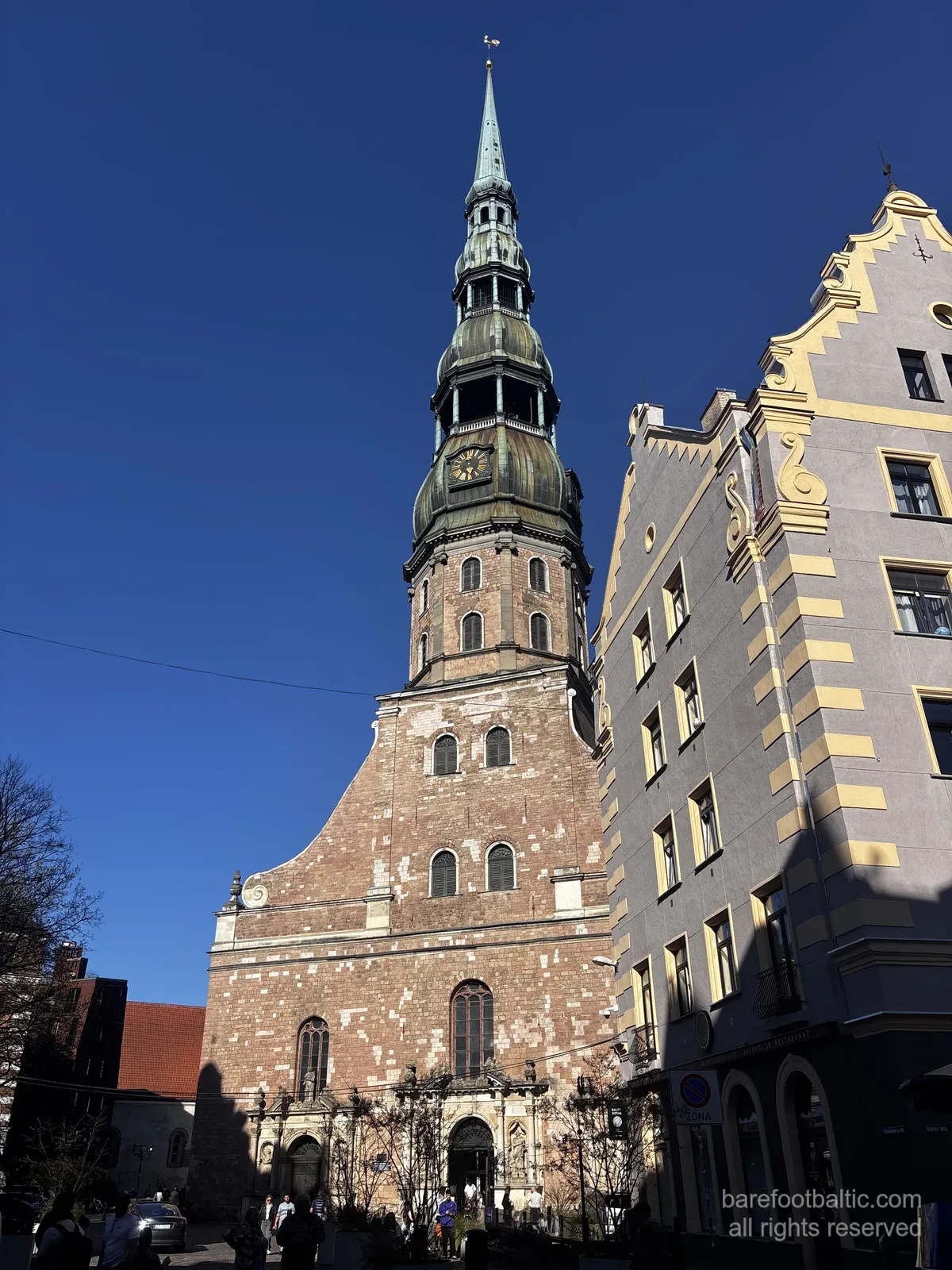 Kościół św. Piotra (Sv. Pētera baznīca) z wysoką zieloną iglicą na tle błękitnego nieba na Starym Mieście w Rydze, Łotwa.
