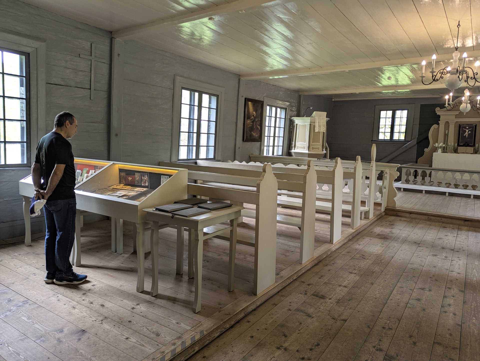 Wnętrze drewnianego muzeum-kościoła Vidzeme z&nbsp;gościem oglądającym ekspozycję