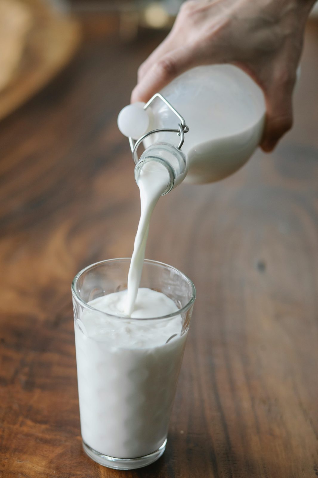 Łotewski kefir przelewany z butelki do szklanki na drewnianym stole